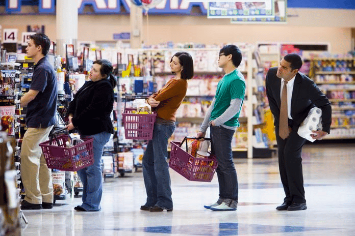 Line of customers waiting for checkout, last person in line is holding their bladder in while clutching toilet paper for purchase