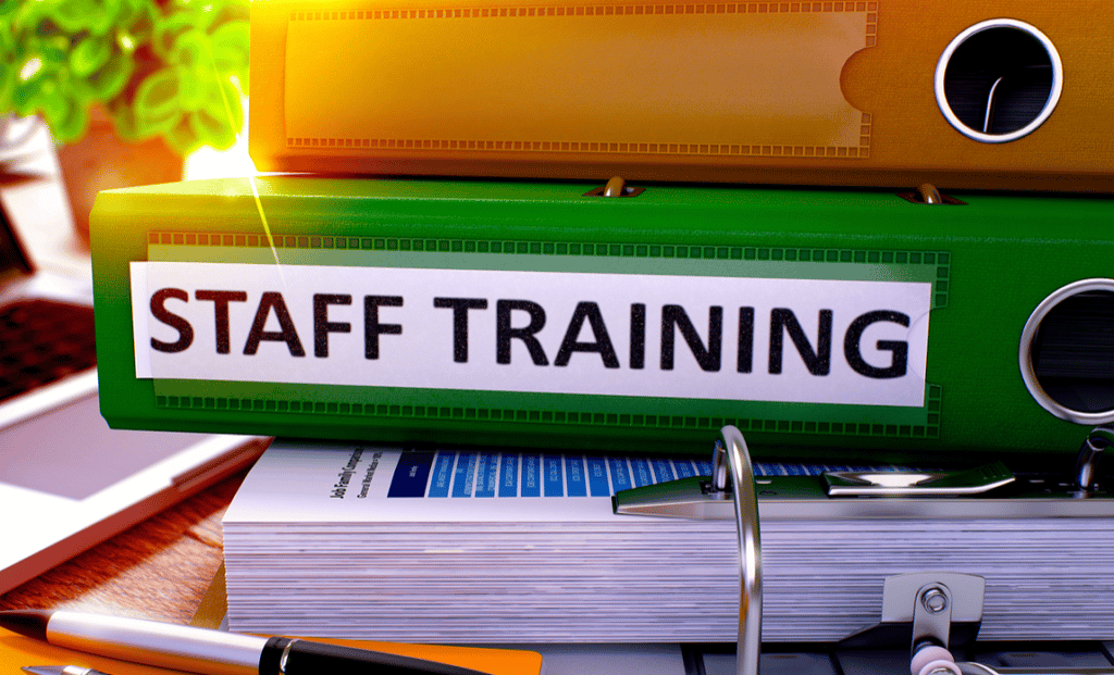 Stacked binders, with the middle one being labelled "STAFF TRAINING"